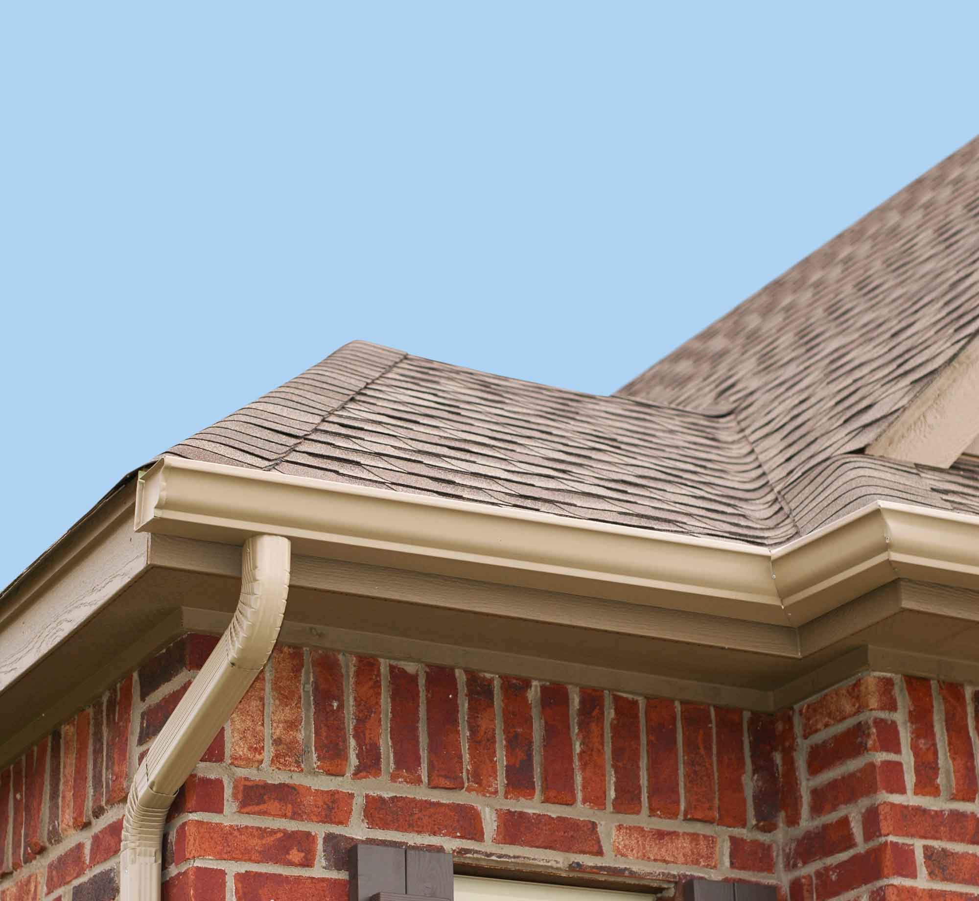 Close-up of quality tan gutter installation on a brick house