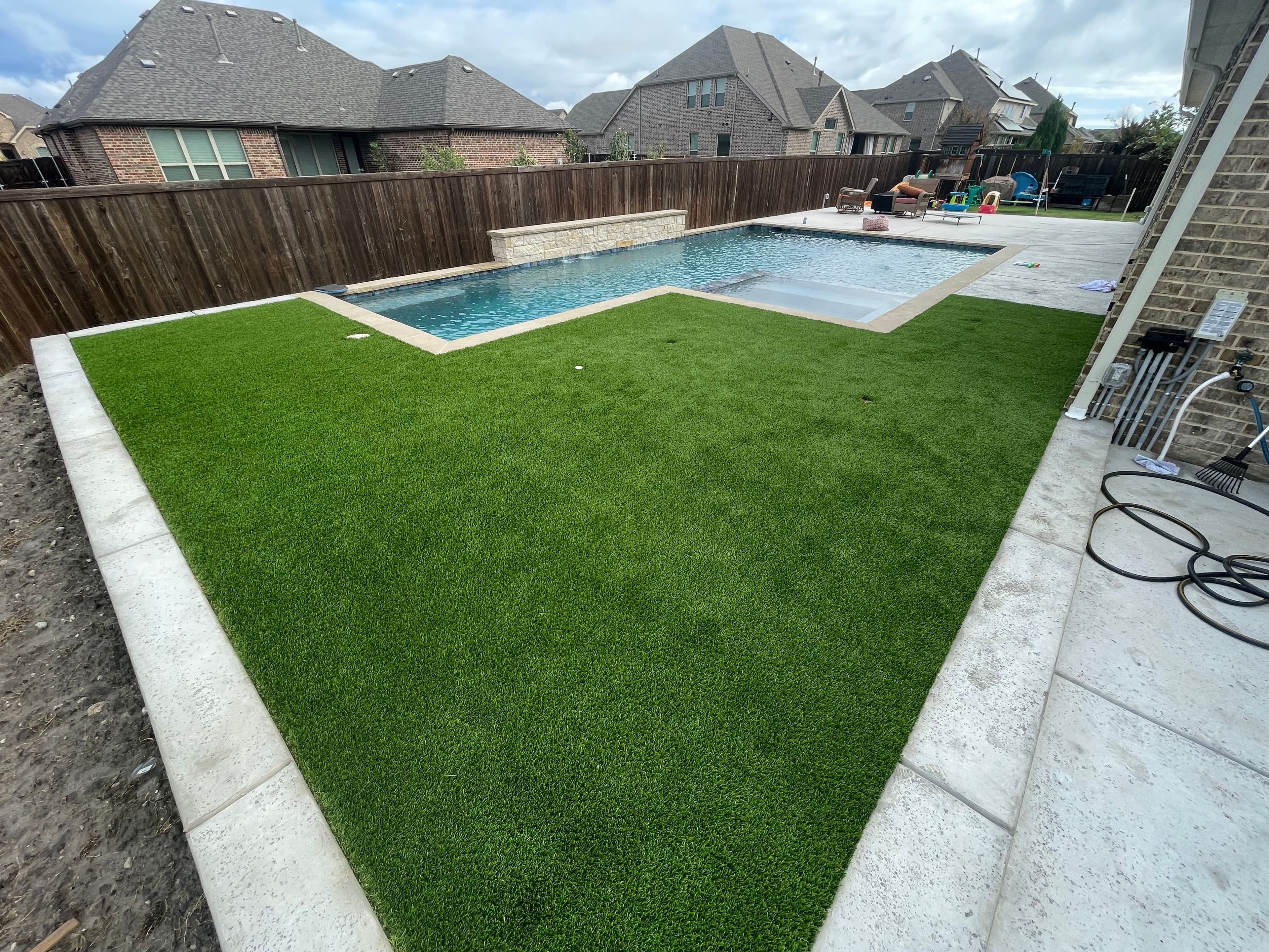 Modern backyard with artificial turf installation around pool