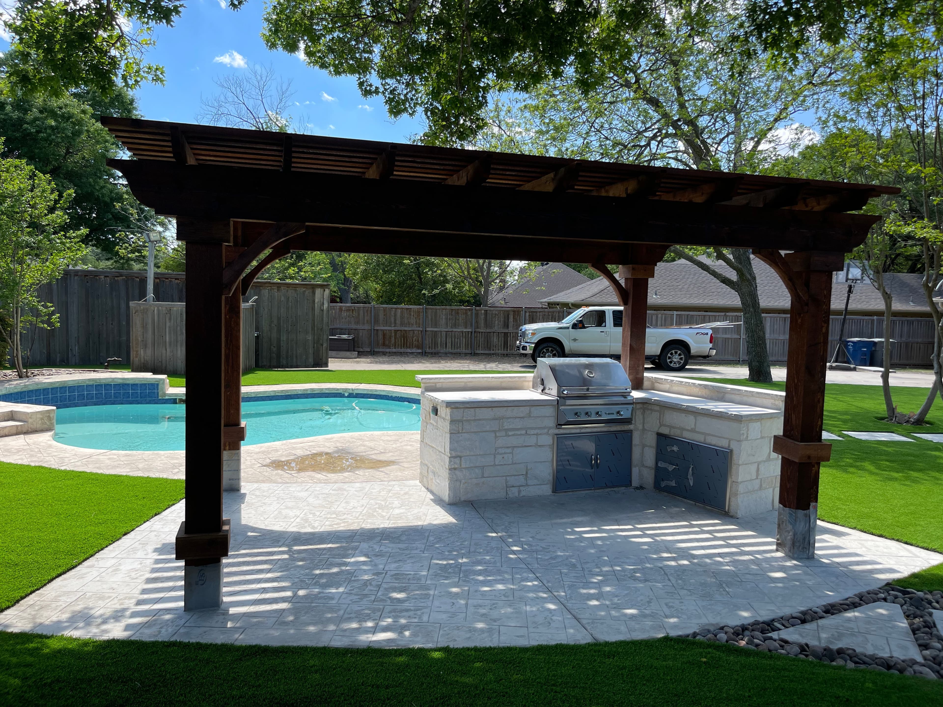 Poolside pergola with built-in grill and stone countertops