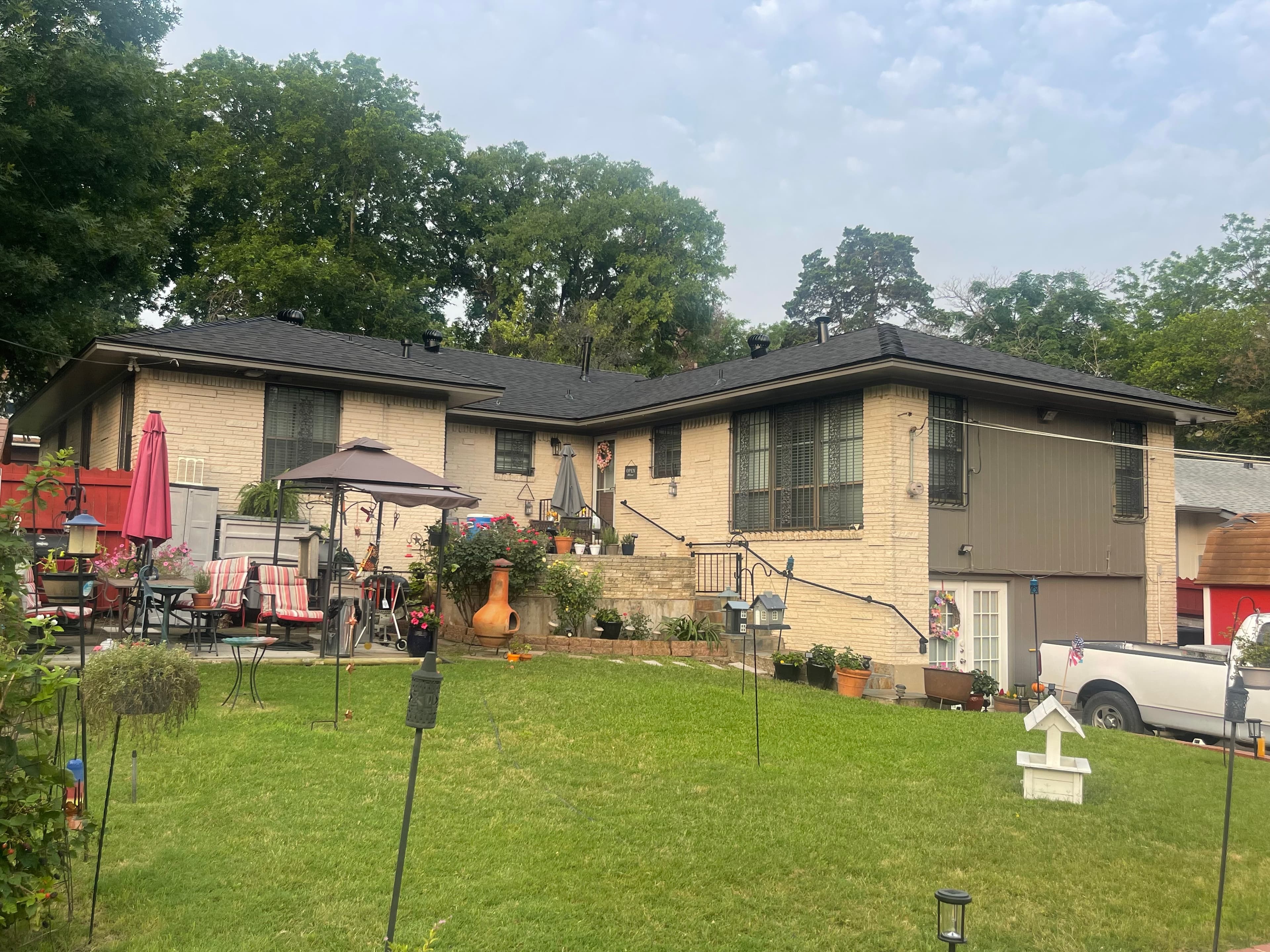 Single-story yellow brick ranch home with black shingle roof