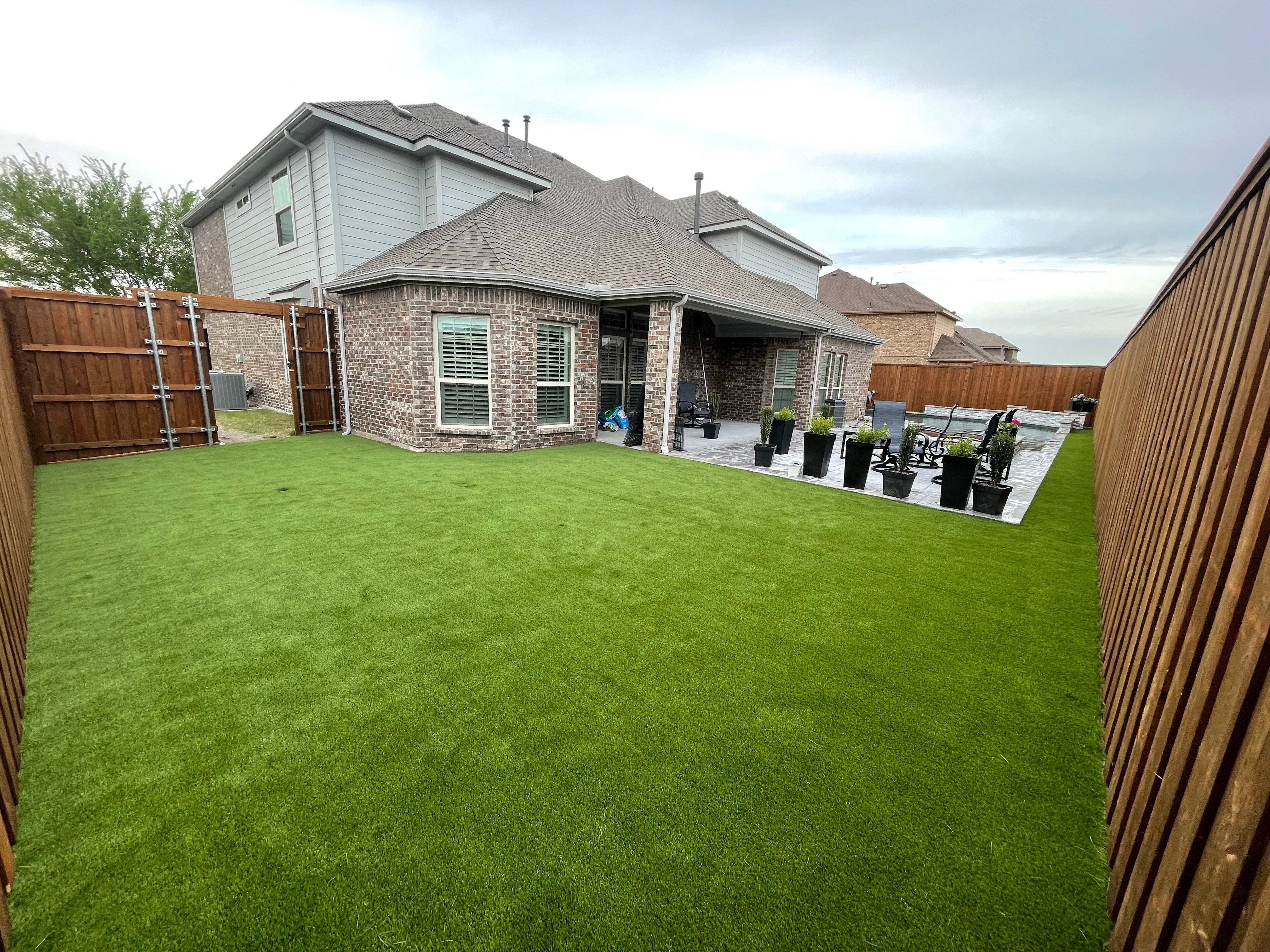 Full backyard artificial turf installation with patio