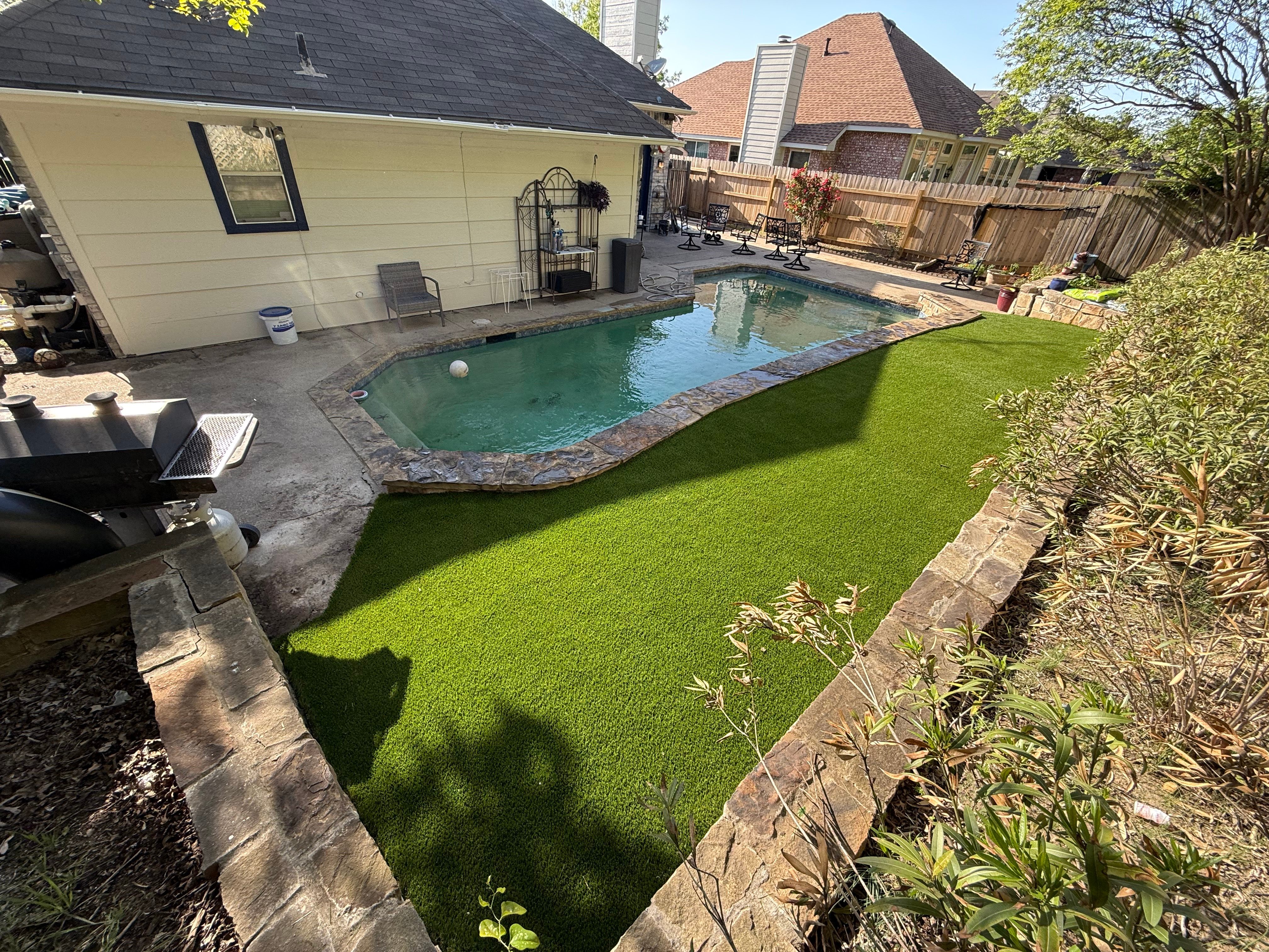Poolside artificial turf installation with stone border
